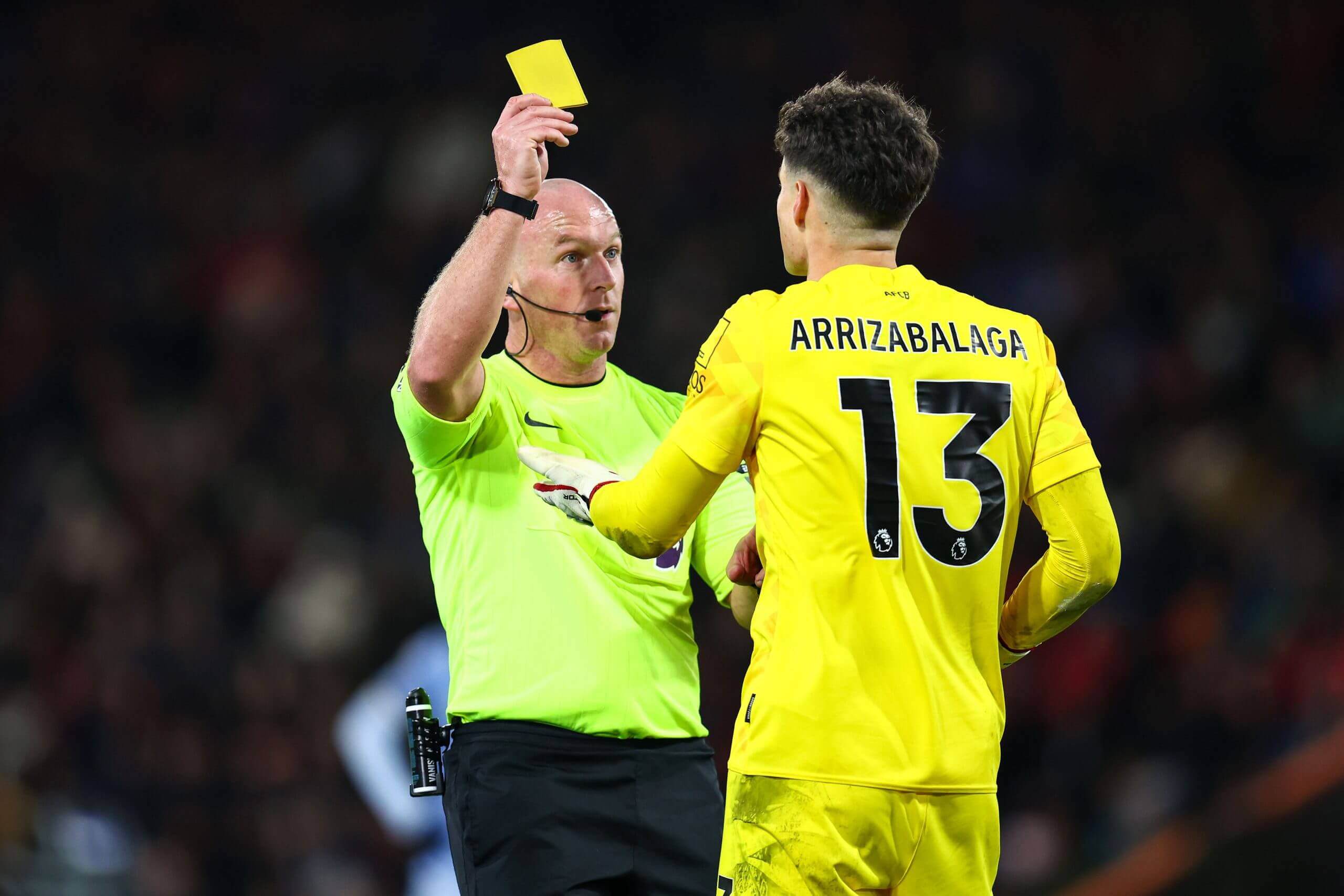 Referee issuing delayed yellow card after advantage sequence showing referee raising card